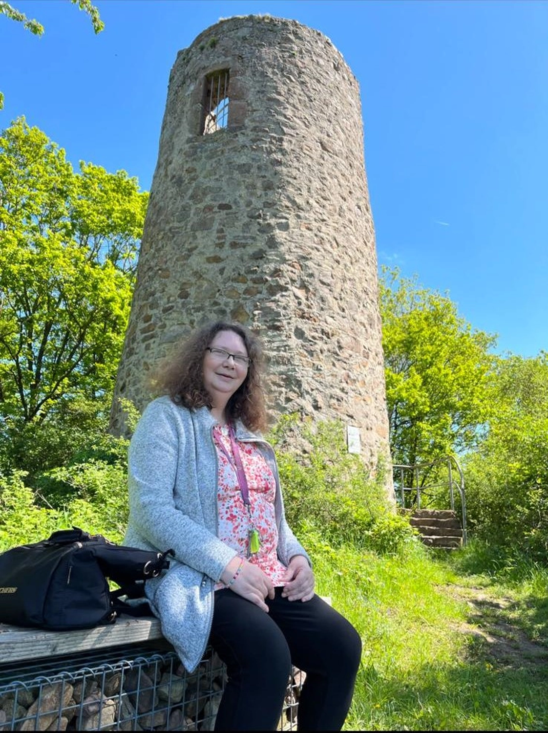 Soziale Teilhabe Kilian und Partner - sozialpädagogische Hilfe - eine Person, die vor einem von Bäumen umgebenen Steinturm sitzt