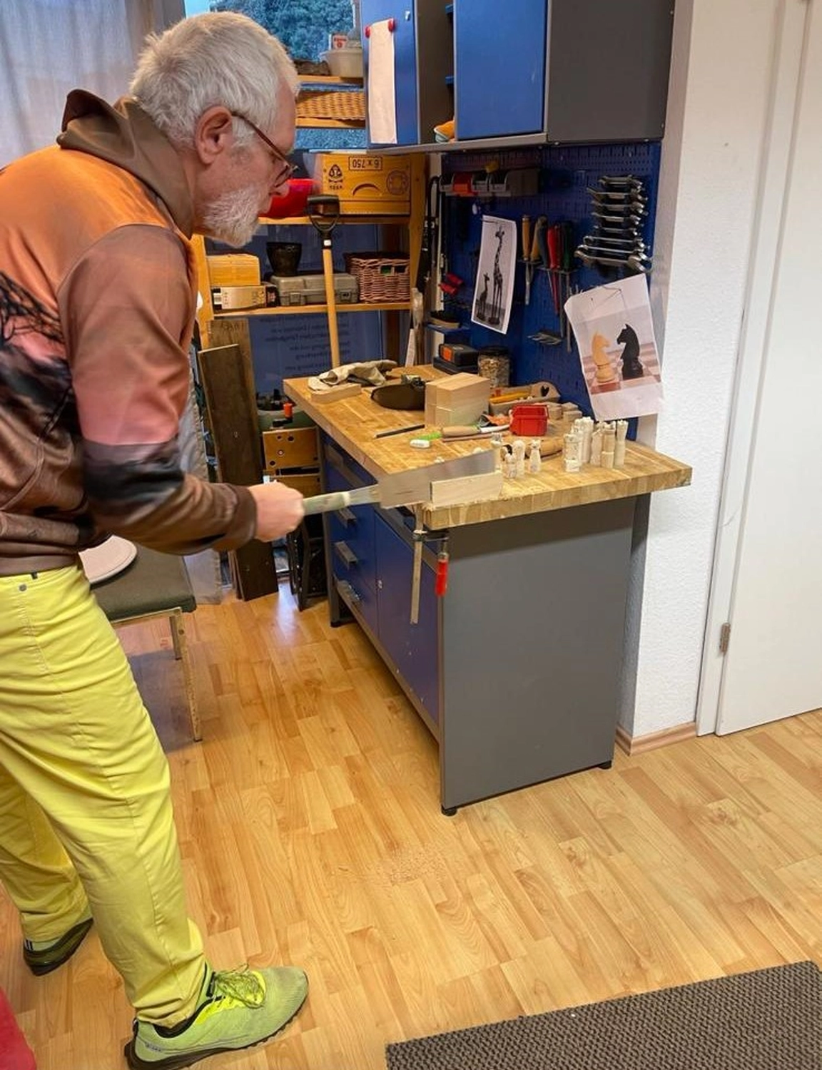 Soziale Teilhabe Kilian und Partner - sozialpädagogische Hilfe - eine Person, die mit einer Handsäge Holzstücke auf einer Werkstattwerkbank schneidet