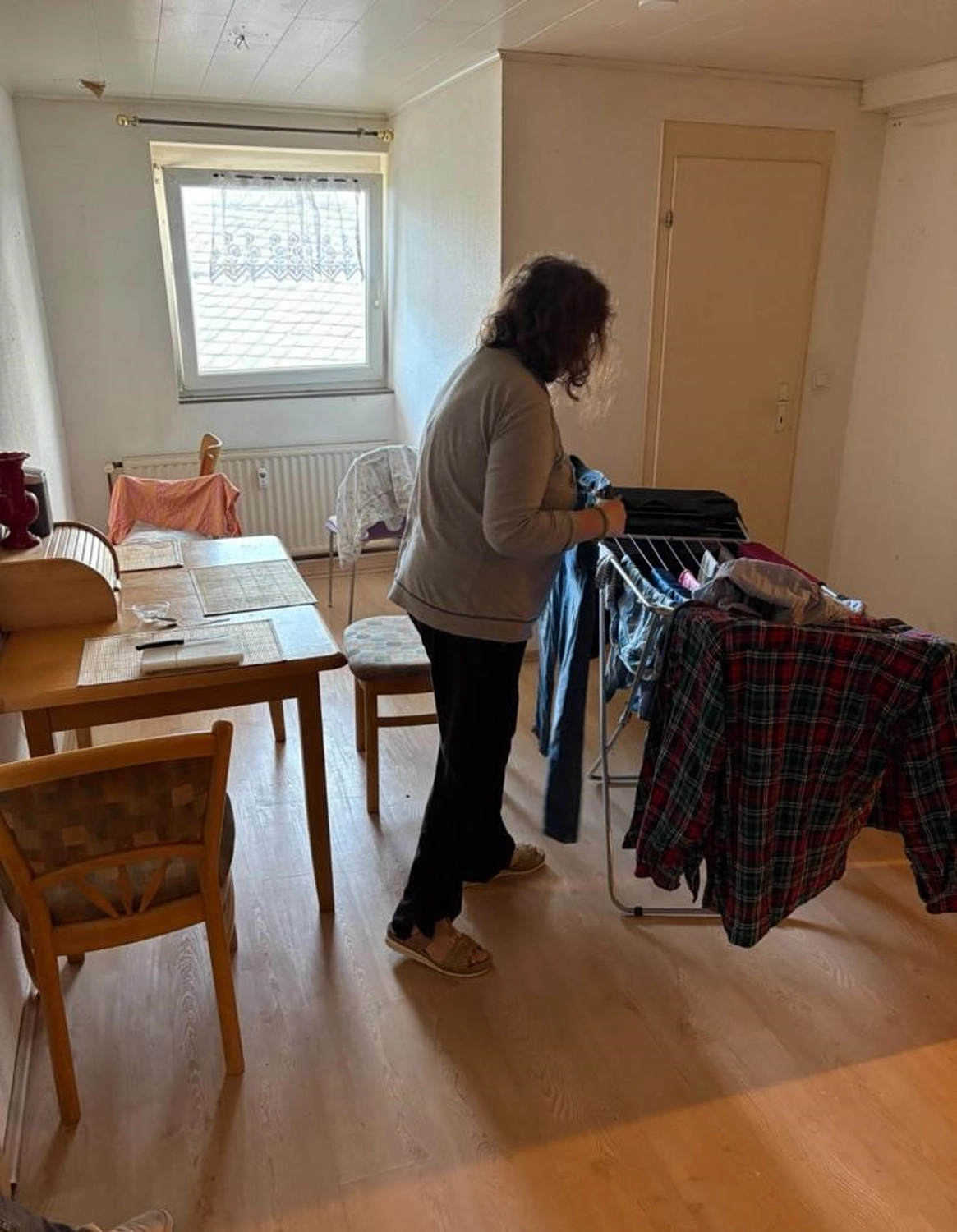 Soziale Teilhabe Kilian und Partner - sozialpädagogische Hilfe - eine Frau hängt Wäsche auf einen Wäscheständer im Innenbereich